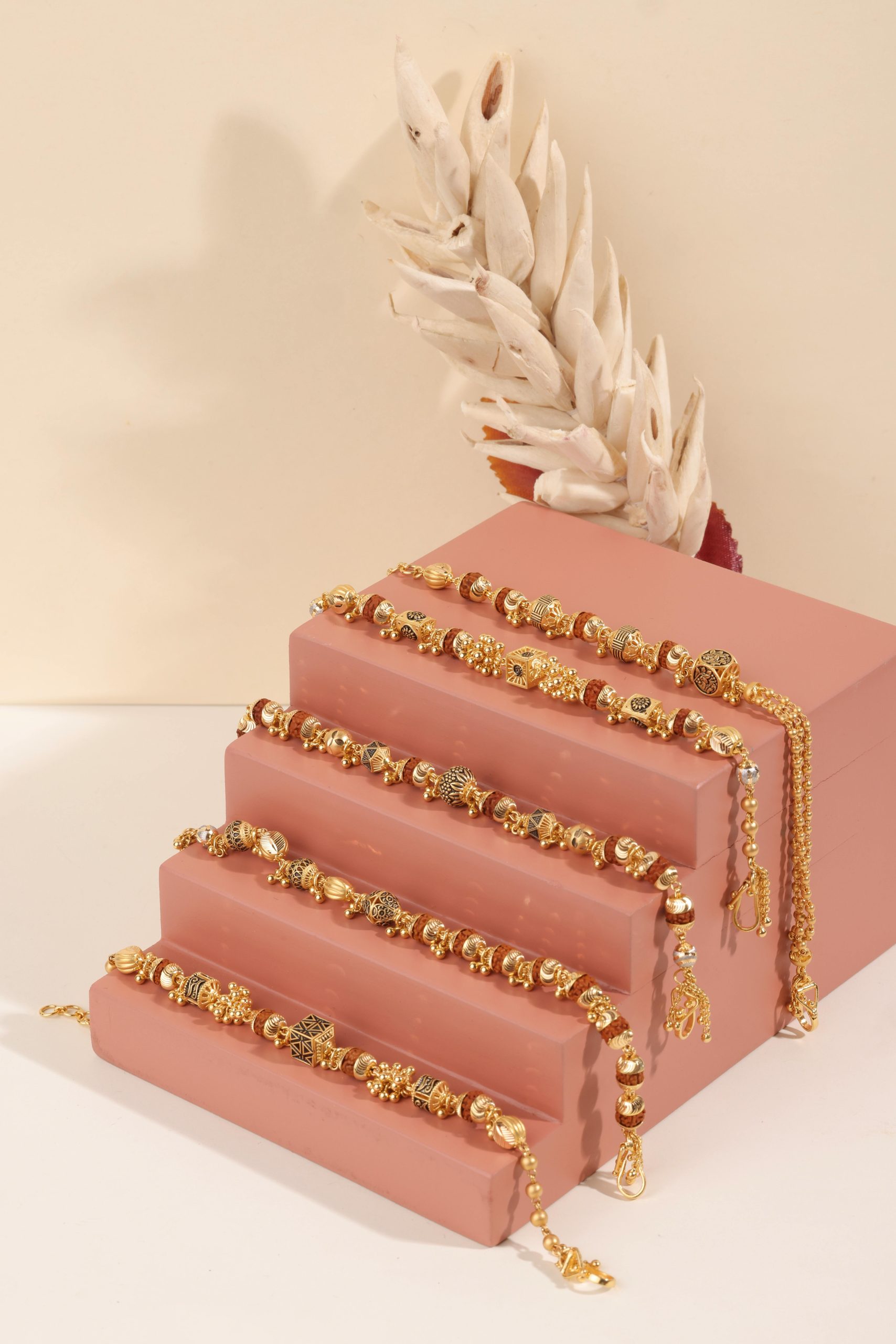 Stylish gold bracelets elegantly displayed on a pink stand with soft lighting highlights.