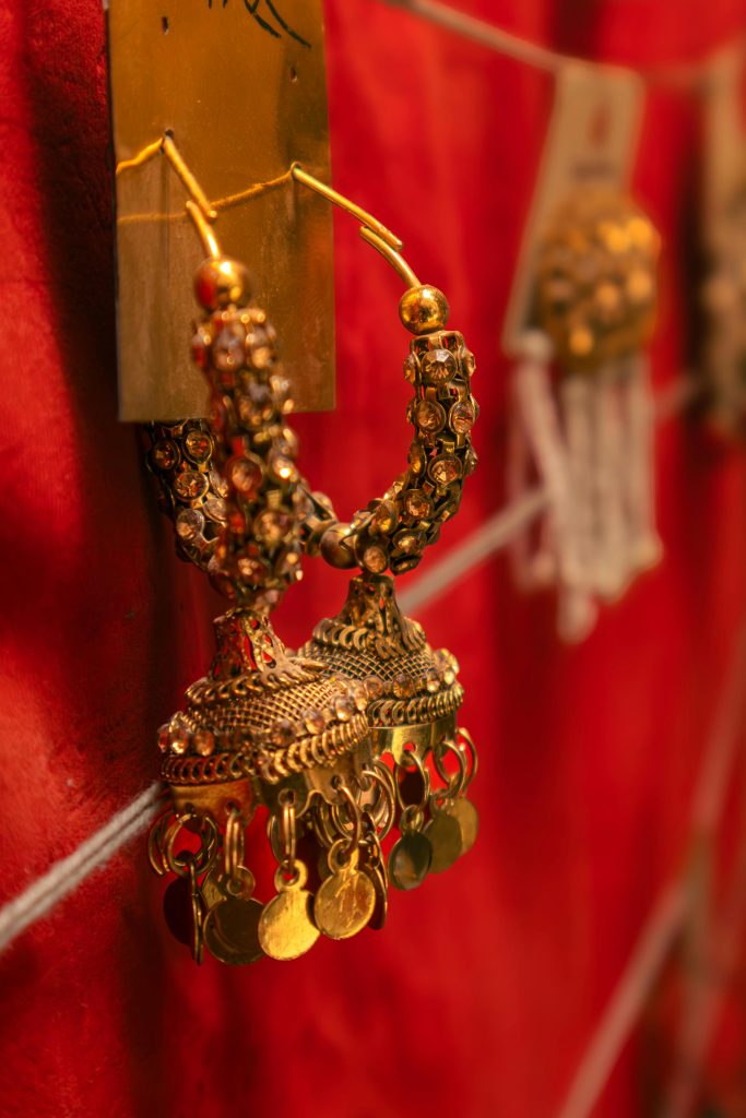 Close-up of ornate traditional Indian earrings set against a rich red background, showcasing intricate details.