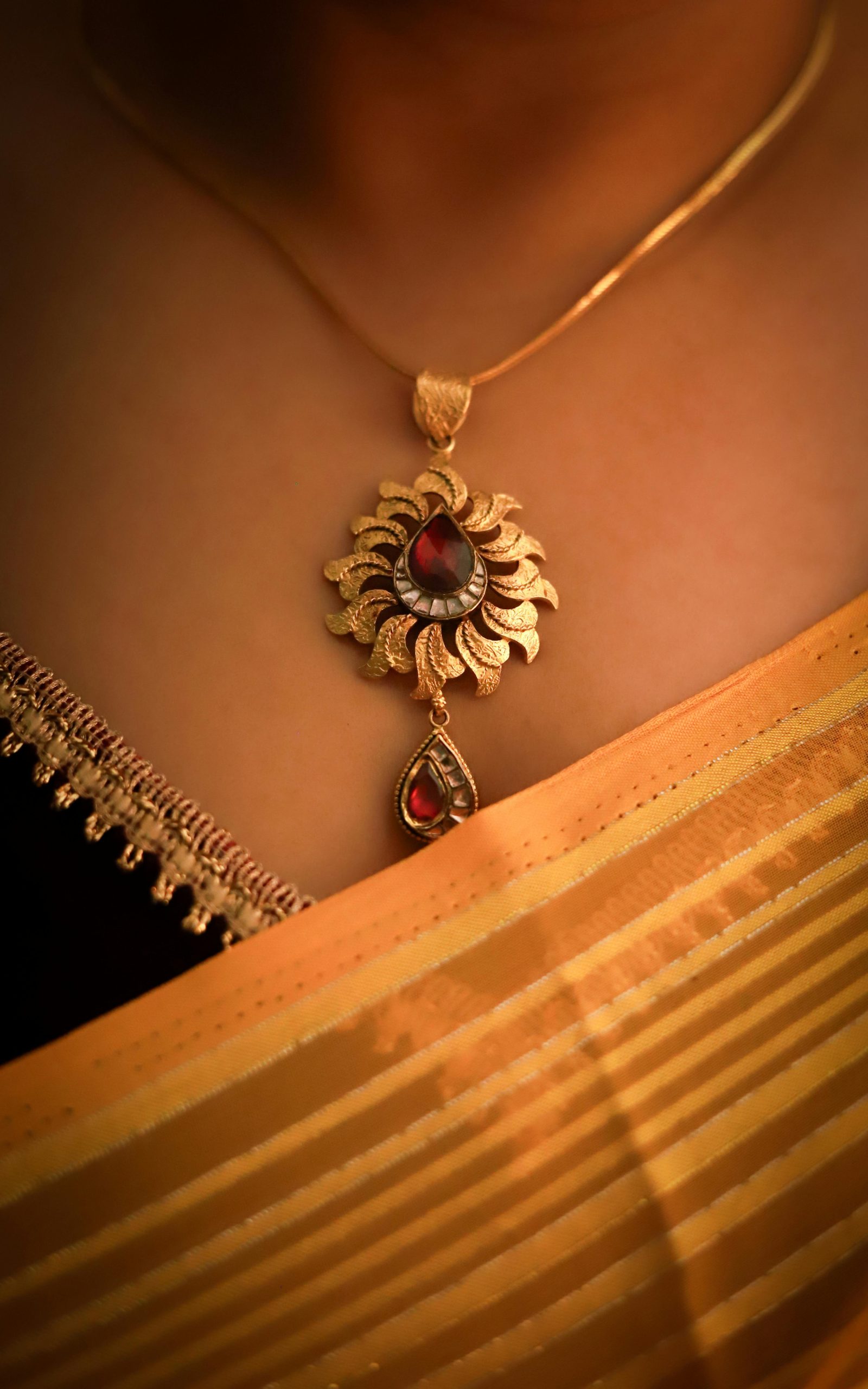 Stylish gold pendant with red gemstone elegantly displayed on a traditional Indian saree.