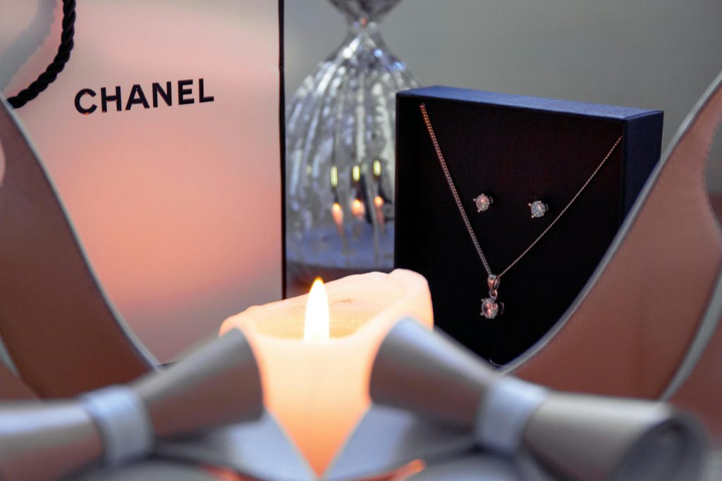 Elegant jewelry set highlighted by warm candlelight and a luxury packaging backdrop.